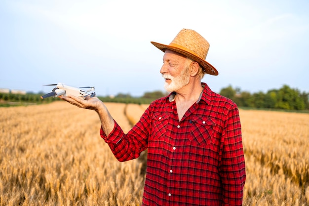 Rolnik stojący na polu pszenicy trzymający drona rolniczego gotowy do startu