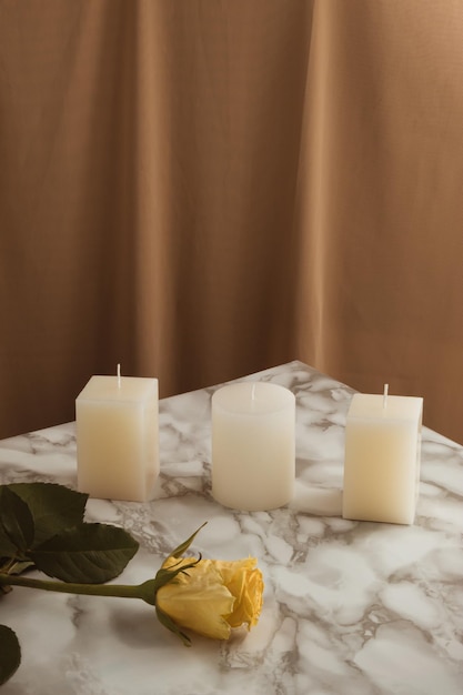 Romantyczna kompozycja ze świecami i żółtym kwiatem róży na marmurowym stole Vintage beżowa zasłona