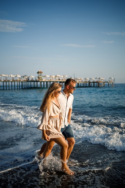 Romantyczna młoda para zakochana razem na piasku spacery wzdłuż plaży Morza Śródziemnego. Letnie wakacje w ciepłym kraju.