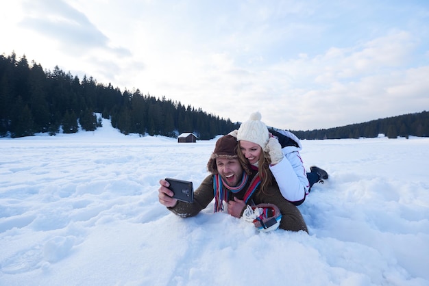 romantyczna para bawi się w świeżym śniegu i robi selfie