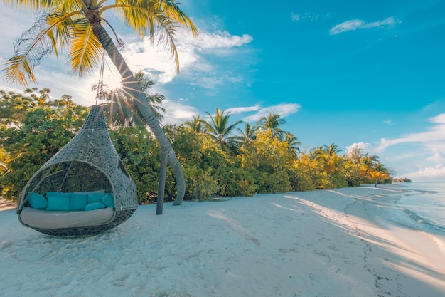 Romantyczna plaża Malediwów pod zachodem słońca z parą huśtawek na palmie kokosowej. Uwielbiam krajobraz podróży