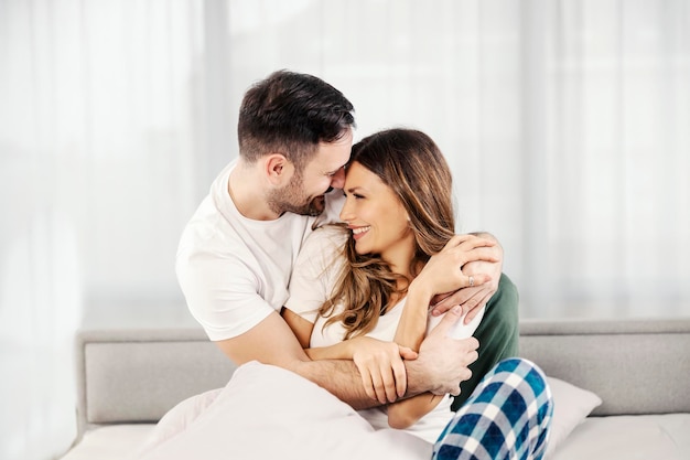 Romantyczna poranna para przytulająca się w łóżku w swoim przytulnym mieszkaniu