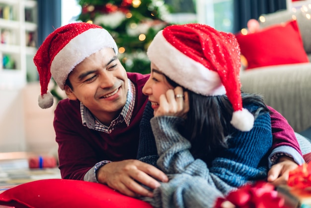 Romantyczna słodka para w czapkach Mikołaja, bawiąc się i uśmiechając, świętując wigilię nowego roku i spędzając razem czas