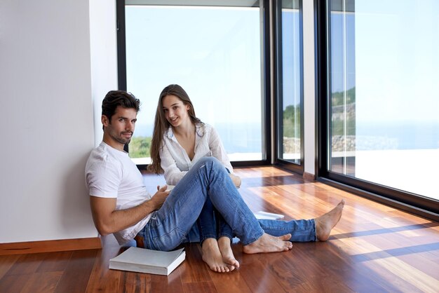 Romantyczna szczęśliwa młoda para relaksuje przy nowożytnym domowym schody indoors