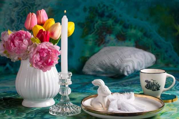 Romantyczne nakrycie stołu wielkanocnego ze świecami biały talerzyk z dzianiny kubek z napojem Dekoracja stołu z królikiem i malowanymi jajkami