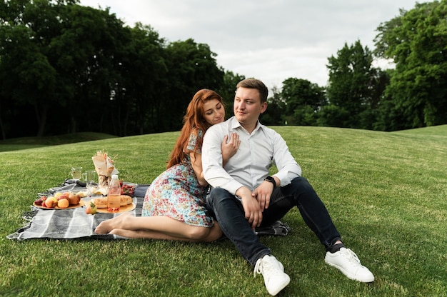 Romantyczny piknik o zachodzie słońca. zakochana para podczas obiadu w parku. czas wakacji letnich. młodzi ludzie na romantycznej randce.