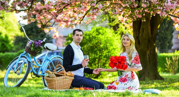 Romantyczny piknik z winem Kwiaty symbol romansu i uczucia Radość z idealnej randki Para relaksuje się w parku na rowerze Szczęśliwi razem Zakochana randka na pikniku Wiosenny weekend