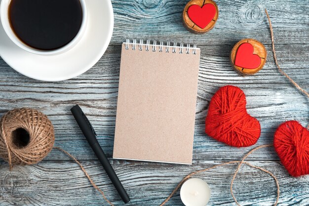 Romantyczny tło z notatnika, filiżanki kawy i serca na podłoże drewniane.