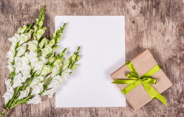 Romantyczny zestaw, delikatne białe kwiaty, pudełko na prezent i czysta kartka papieru.
