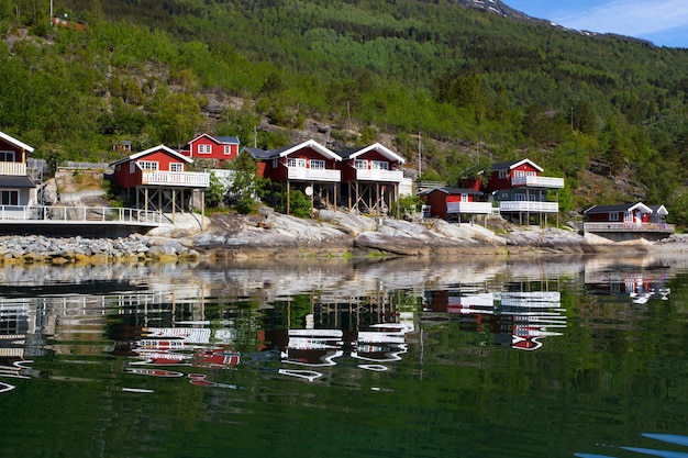 Rorbuer - tradycyjny norweski czerwony drewniany dom do postawienia nad jeziorem i górami w oddali, norwegia