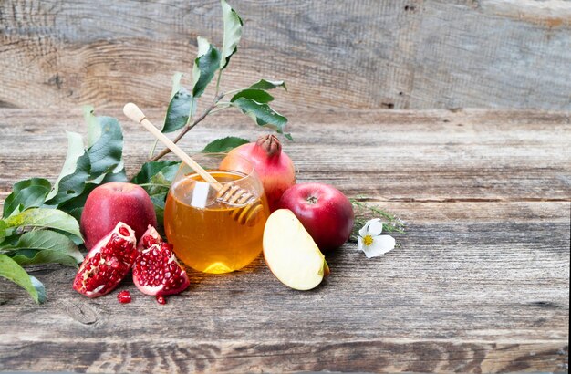 Rosh Hashana świąteczny dzban z miodem z jabłkami i granatami na wiejskim tle