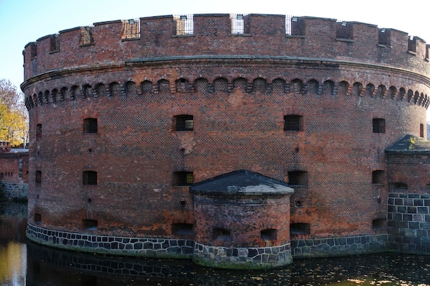 Rosja Kaliningrad Październik 31 2022Stary ceglany okrągły fort z otworami strzelniczymi z czerwonej cegły i fosą wypełnioną wodą