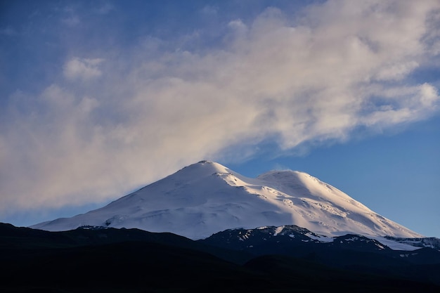 Rosja Kaukaz Góra Elbrus majestatycznie ozdobiona pierwotnym śniegiem i lodem Krajobraz alpejski szczyci się panoramicznymi widokami na nierówne grzbiety spokojne doliny i lodowce pod rozległym niebieskim niebem