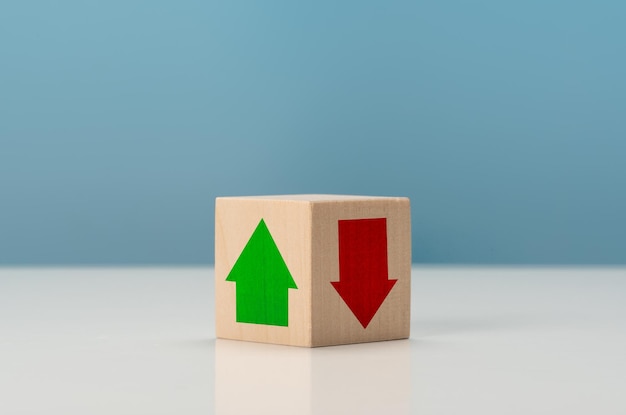 Rosnące i opadające trendy zielona strzałka w górę po jasnej stronie i czerwona strzałka w dół po ciemnej stronie, która drukuje ekran na drewnianym bloku kostki dla koncepcji wzrostu zysku gospodarczego i biznesowego