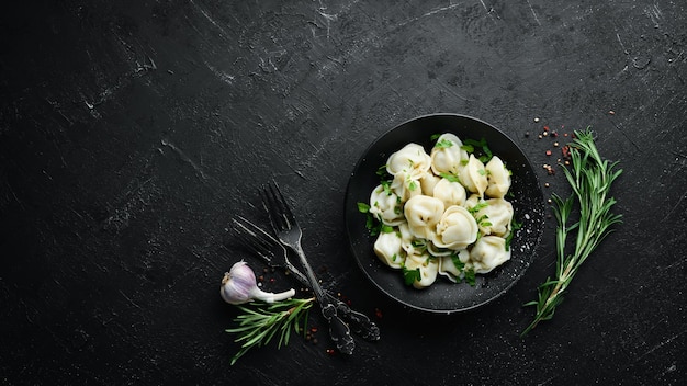 Rosyjskie mięso pelmeni Pierogi z zieleniną na czarnym talerzu Rosyjska tradycyjna kuchnia Widok z góry Darmowe miejsce na kopię