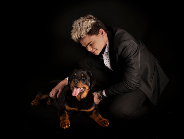 Rottweiler czystej krwi i nastolatek na czarnym tle