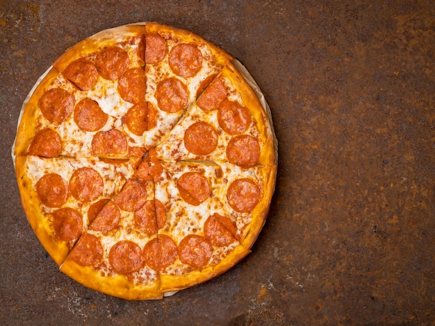 Round Włoska pizza pepperoni na ośniedziałym metalu biurka odgórnym widoku, opróżnia przestrzeń dla teksta.