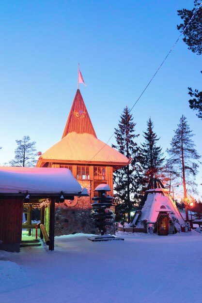 Zdjęcie rovaniemi, finlandia - 6 marca 2017: główny urząd pocztowy świętego mikołaja w santa village z choinkami w laponii, finlandia, skandynawia na kole podbiegunowym w zimie. noc. na wolnym powietrzu