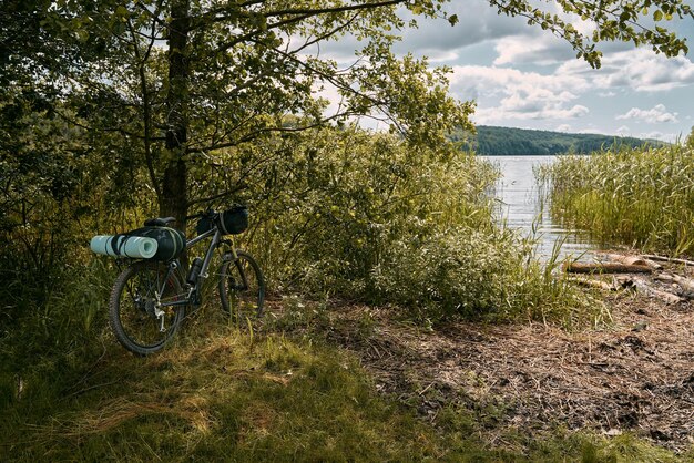 Rower jest zapakowany w wiele toreb i innego sprzętu gotowego na przygodę i podróż Turystyka na rowerze górskim Przygody pakowania rowerów w lesie i nad jeziorami Bagażnik na rowerze