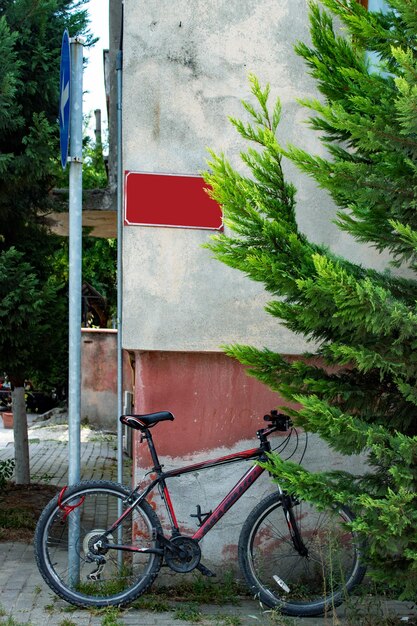 Rower oparty o ścianę na ulicy. Pusty obszar postu na ścianie czerwony szyld.