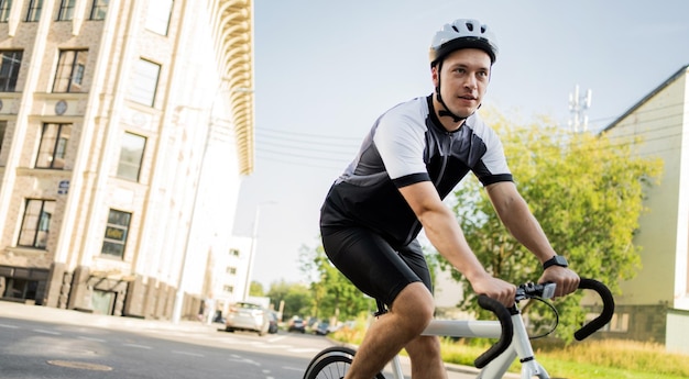 Rowerzysta eko transport jeździ na rowerze w miejskim kombinezonie rowerowym i kasku na sportowcu