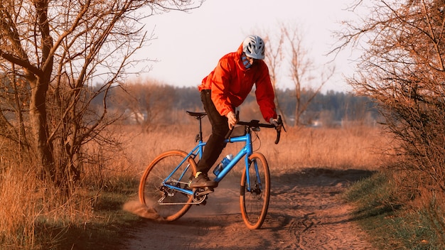 Rowerzysta Na Rowerze Szutrowym Jeździ Po Drodze, Zbierając Kurz Z Zachodu Słońca. Jazda Na Rowerze Szutrowym. Koncepcja Sportów Ekstremalnych I Aktywności.