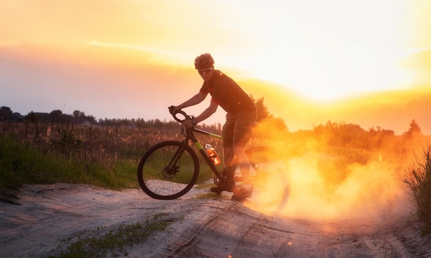 Rowerzysta na rowerze szutrowym jeździ po szlaku wznosząc kurz z tylnego koła