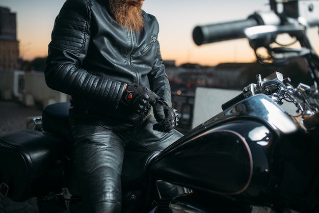 Rowerzysta pozuje na motocyklu w mieście na zachód słońca, klasyczny chopper. Rower vintage, swobodny styl życia, jazda na rowerze