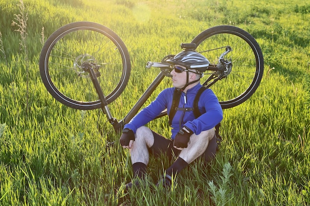 Rowerzysta siedzący na trawie obok roweru