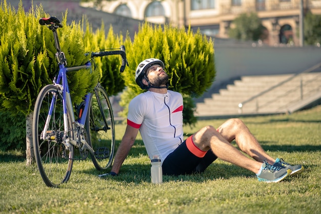 Rowerzysta siedzi na trawie w pobliżu roweru