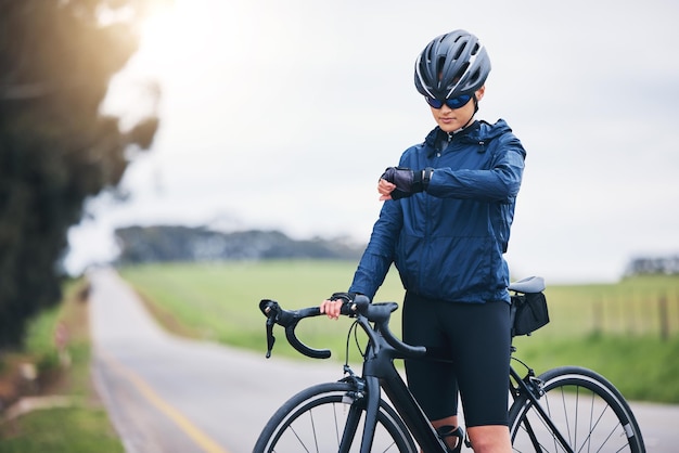 Rowerzysta sprawdza czas i przyrodę na drodze pod kątem prędkości gps i tętna z celem fitness, zdrowia i dobrego samopoczucia Jazda na rowerze i lekkoatletka z zegarkiem do treningu i treningu