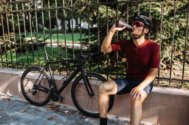 Rowerzysta w kasku odświeżający wodą po treningu