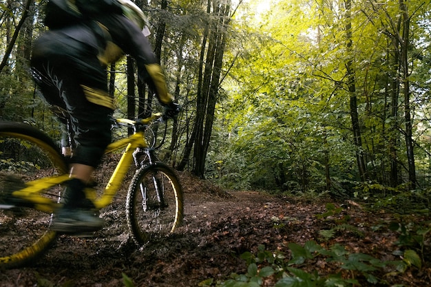 Rowerzysta W Kasku Pełnotwarzowym Na żółtym Rowerze Enduro Szybko Jeździ W Błocie W Zielonym Lesie