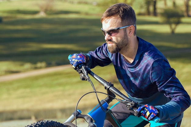 Rowerzysta w krótkich spodenkach i koszulce na nowoczesnym rowerze hardtail z włókna węglowego z widelcem pneumatycznym