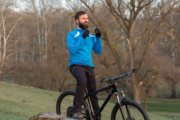 Rowerzysta W Spodniach I Polarowej Kurtce Na Nowoczesnym Rowerze Hardtail Z Włókna Węglowego Z Widelcem Pneumatycznym Facet Na Szczycie Wzgórza Jeździ Na Rowerze