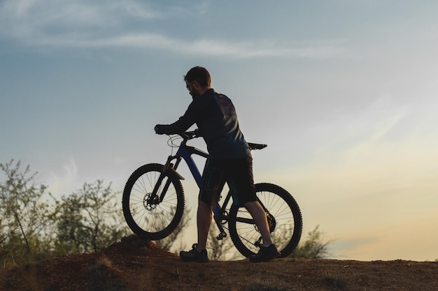 Rowerzysta w spodniach i polarowej kurtce na nowoczesnym rowerze hardtail z włókna węglowego z widelcem pneumatycznym Facet na szczycie wzgórza jeździ na rowerze