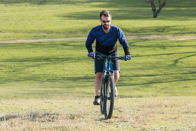 Rowerzysta w spodniach i polarowej kurtce na nowoczesnym rowerze hardtail z włókna węglowego z widelcem pneumatycznym Facet na szczycie wzgórza jeździ na rowerze