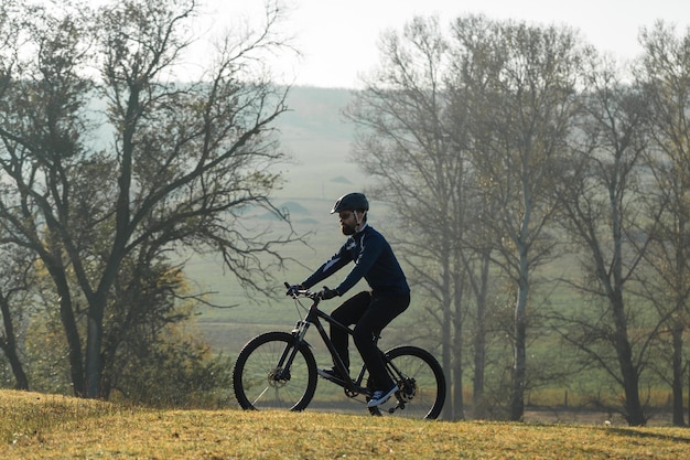 Rowerzysta w spodniach i polarowej kurtce na nowoczesnym rowerze hardtail z włókna węglowego z widelcem pneumatycznym jeździ w terenie