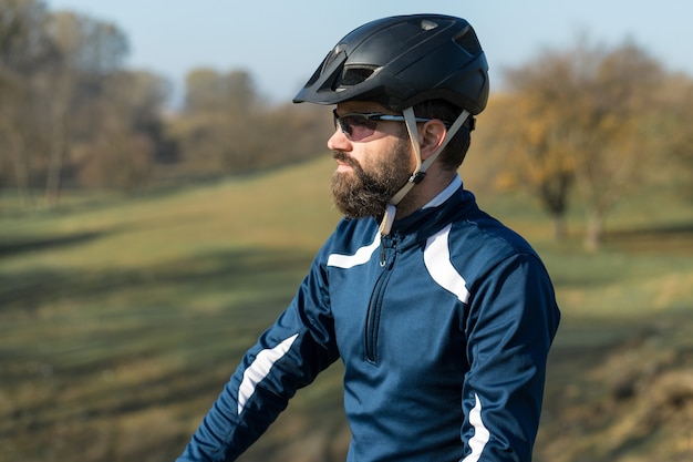 Rowerzysta w spodniach i polarowej kurtce na nowoczesnym rowerze hardtail z włókna węglowego z widelcem pneumatycznym jeździ w terenie.