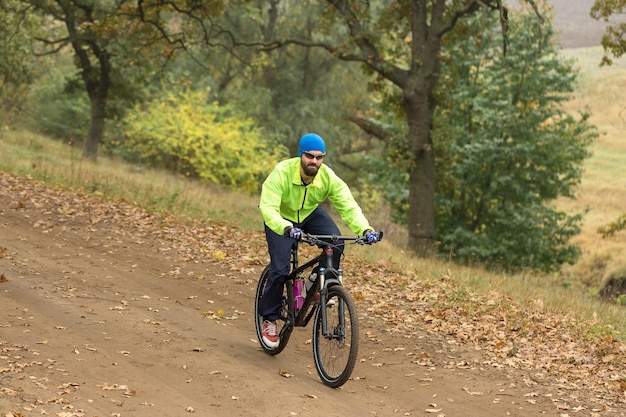 Rowerzysta w spodniach i zielonej kurtce na nowoczesnym rowerze hardtail z włókna węglowego z widelcem pneumatycznym