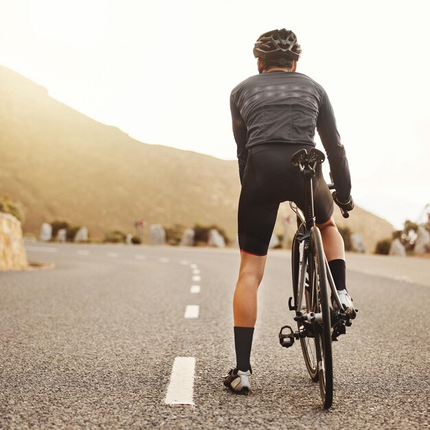 Rowerzysta wiejski rower szosowy lub fitness do treningu o wschodzie słońca i ćwiczeń dla celów zdrowotnych wellness lub cardio sportowiec lub sportowiec rowerowy na australijskiej ulicy z kaskiem