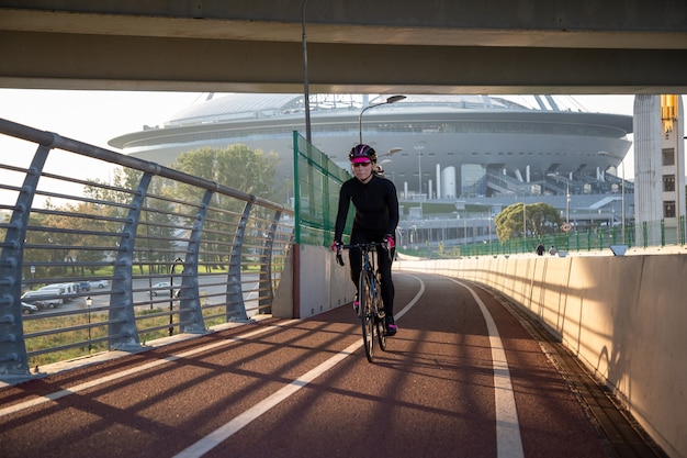 Rowerzystka sportsmenka przejeżdża przez most o wschodzie słońca