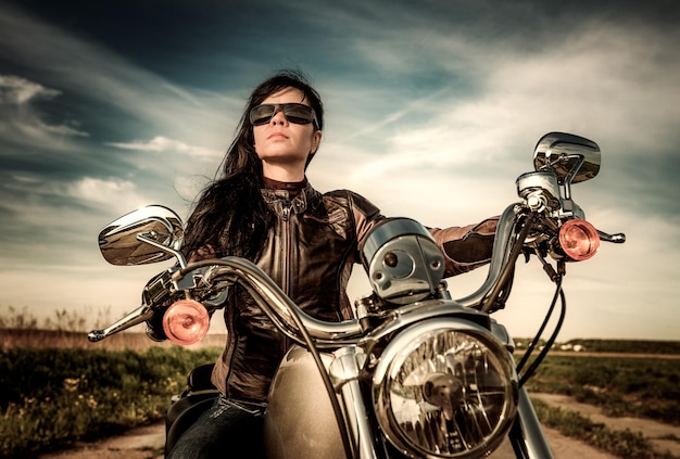 Rowerzystka w okularach przeciwsłonecznych siedząca na motocyklu