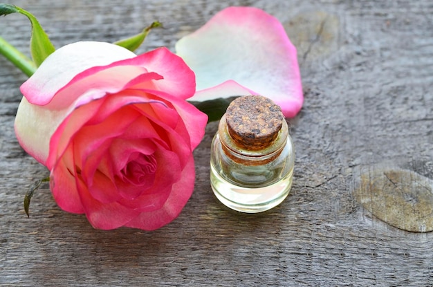 Zdjęcie różany olejek eteryczny w szklanej butelce na starym drewnianym stolekoncepcja pielęgnacji skóry lub aromaterapii w spa