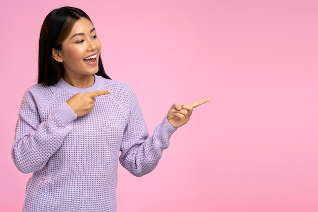 Rozbawiona młoda kobieta wskazując palcem na koncepcję reklamy pustej przestrzeni kopii