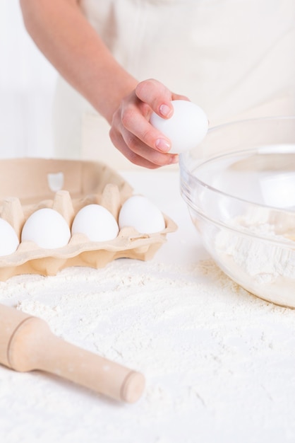 Rozbijanie jajka. Zbliżenie kobiety pęka jajko na ciasto