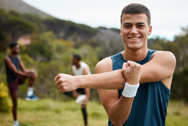 Zdjęcie rozciąganie fitness i portret mężczyzny na świeżym powietrzu dla zdrowia i dobrego samopoczucia szczęśliwy biegacz lub sportowiec w parku przyrody, aby rozpocząć trening lub trening z rozgrzewką mięśni ramion