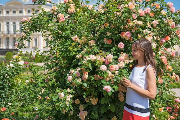 Róże Uprawiają Ogródek I Uśmiechnięta Szczęśliwa Kobieta Na Pogodnym Letnim Dniu.
