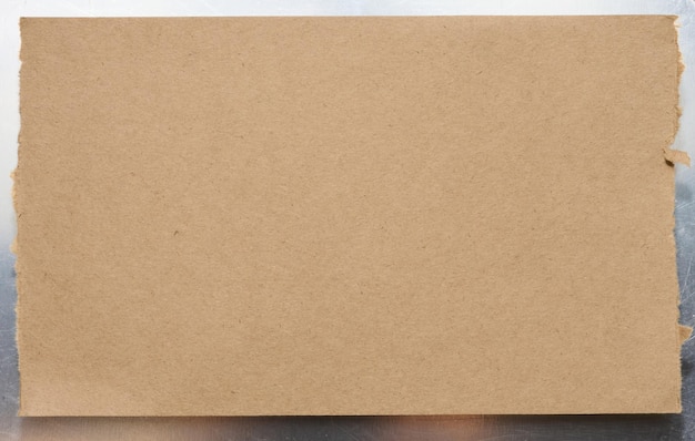 Zdjęcie rozerwany kawałek brązowego kartonu na szarym tle dla inskrypcji