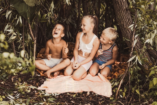 Roześmiane dzieci bawią się w chatce z gałązek i liści. Drewniany dom we wsi